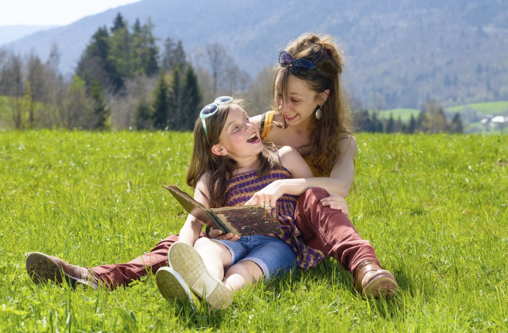 Mom and daughter reading a book in nature